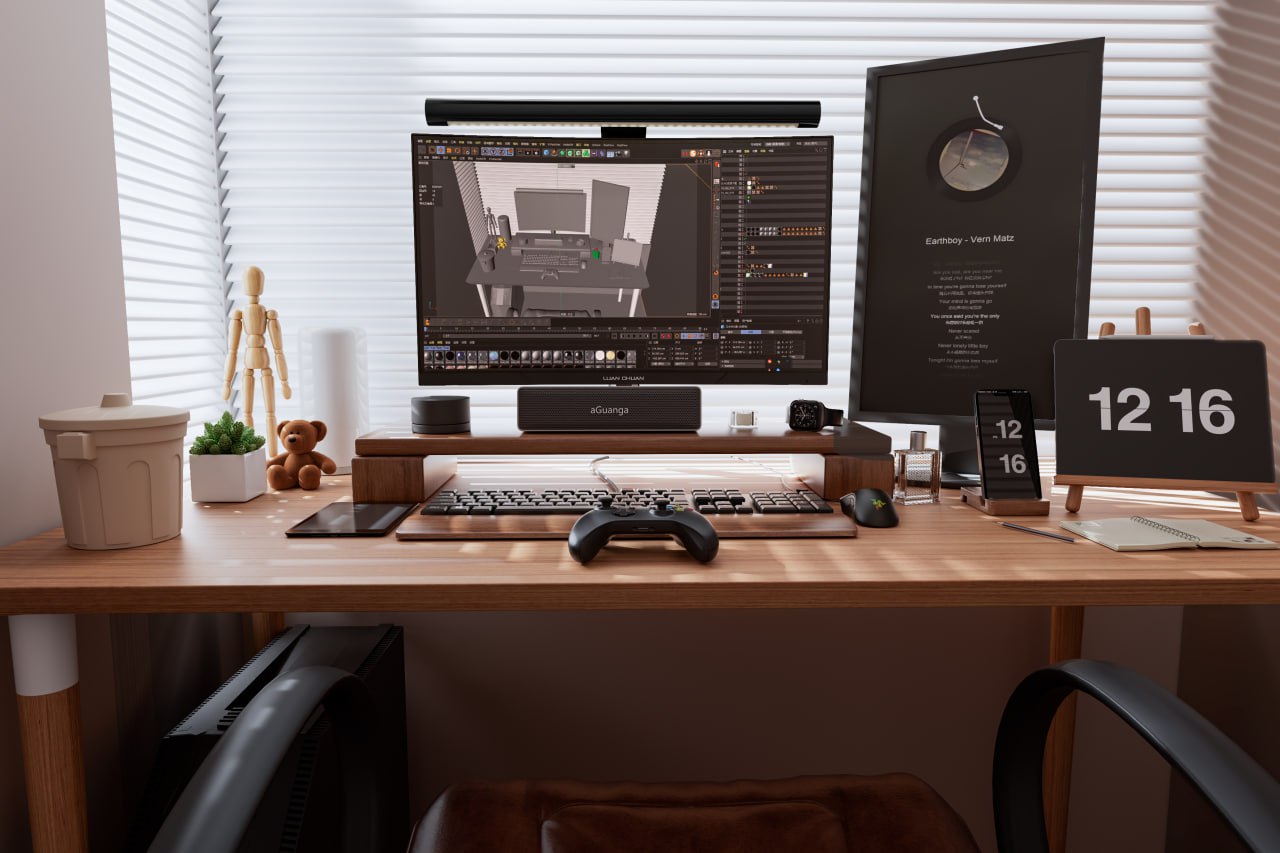 A desk by a window with blinds: a monitor showing a 3D scene, a wooden figure, a clock reading 12:16 and a game controller.