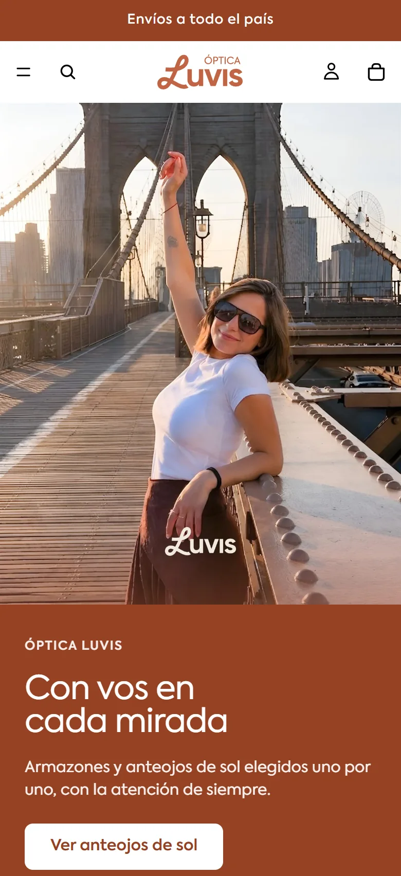 Óptica Luvis home page on a phone: a woman in sunglasses on the Brooklyn Bridge, under a banner announcing shipping nationwide.