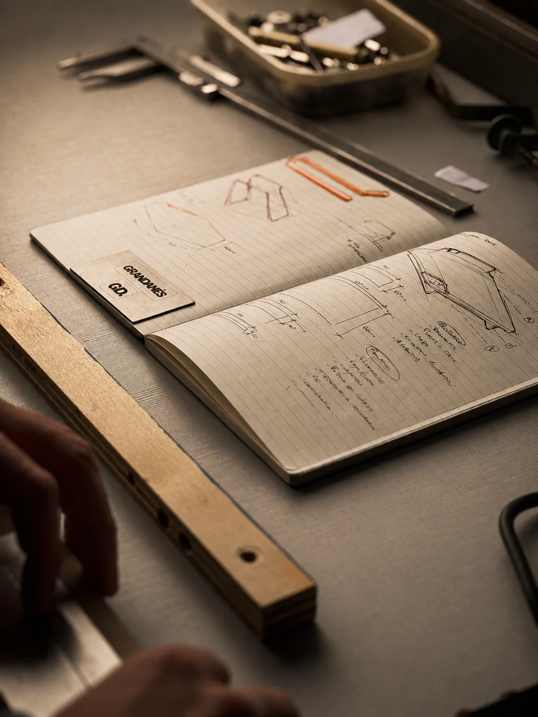 A notebook of Vetra sketches on a workbench, beside a ruler and a tray of screws.