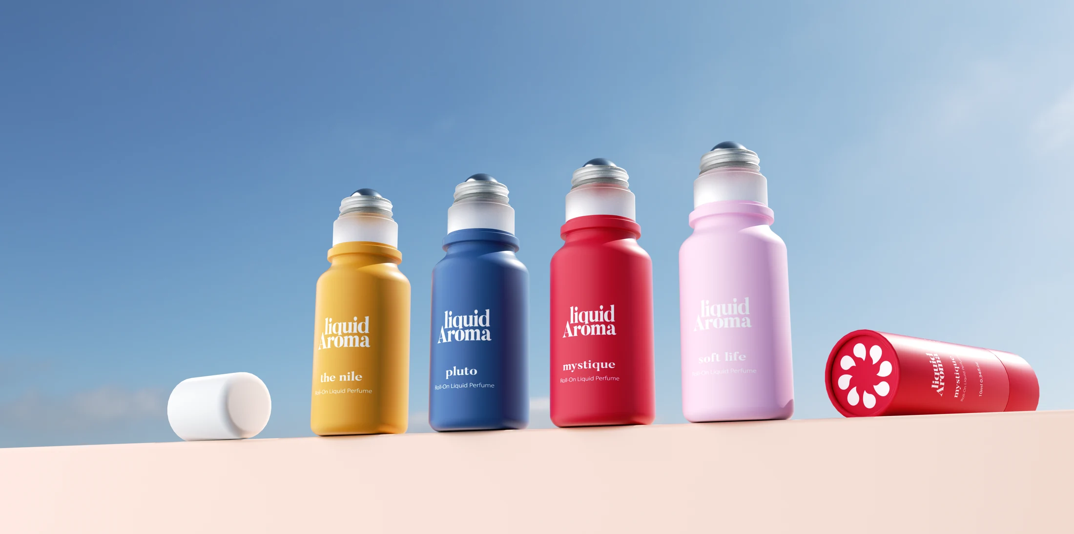 Four roll-on bottles in a row, in orange, blue, red and pink, with a cap and a red tube lying beside them, against a blue sky.